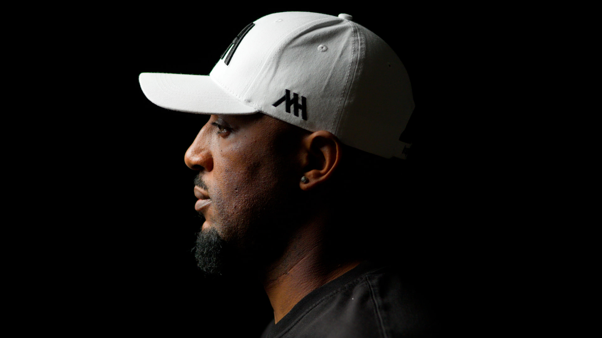 Mudiwa Hood in profile wearing a white MH cap